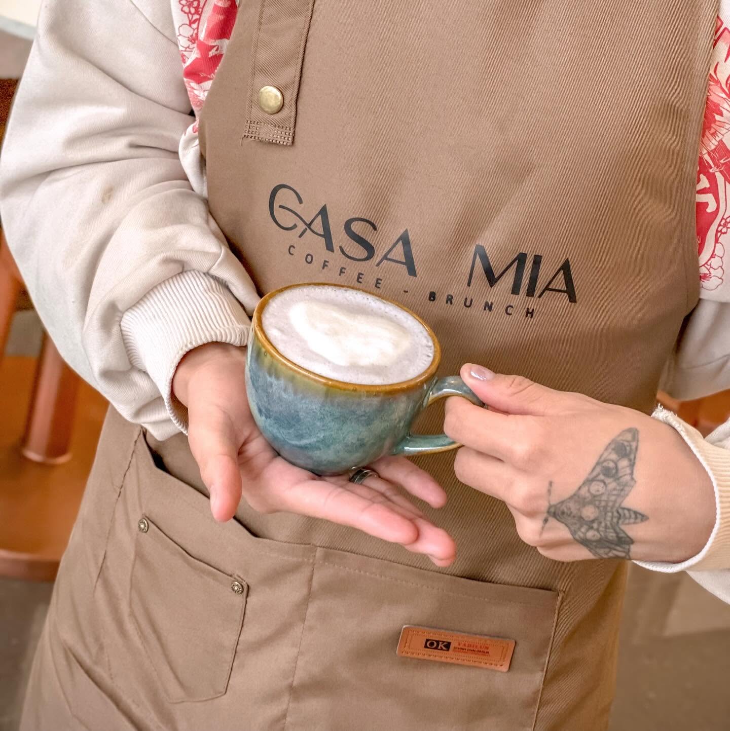 Barista de CASA MIA sosteniendo una taza de cerámica artesanal con latte